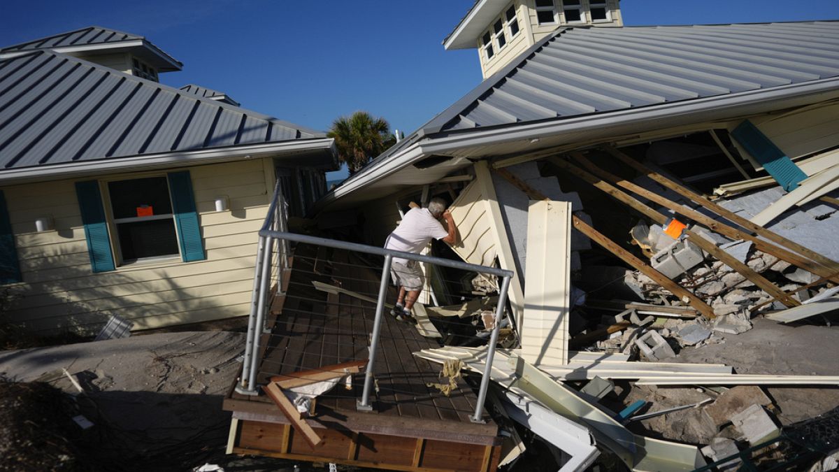 A property owner name peers into the remains of the second floor unit where he lived with his wife, on Manasota Key, in Englewood, Florida, on Sunday