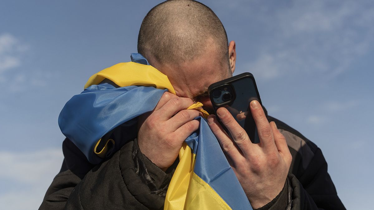 A recently swapped Ukrainian prisoner of war cries while calling his relatives after a prisoner exchange on the Ukrainian Russian border