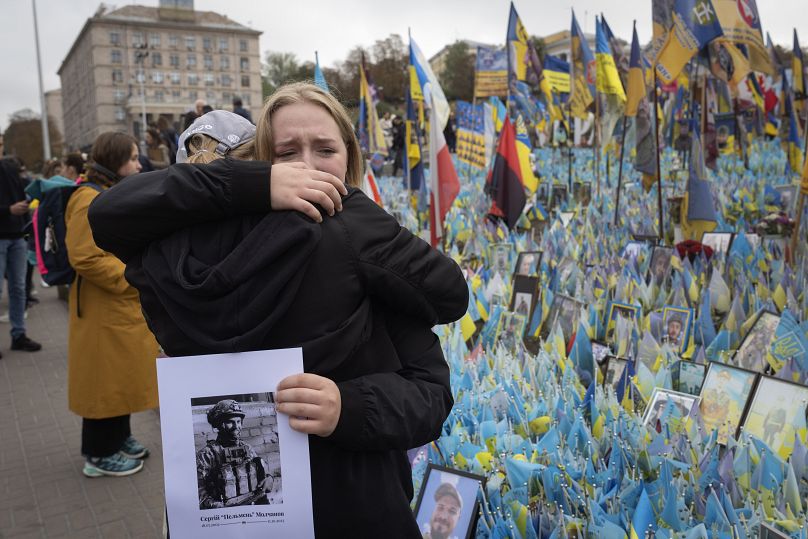 Les gens réagissent lors d'une minute de silence nationale à la mémoire des soldats tombés au combat lors de la Journée des défenseurs, au mémorial de guerre improvisé sur la place de l'Indépendance à Kiev, en Ukraine.