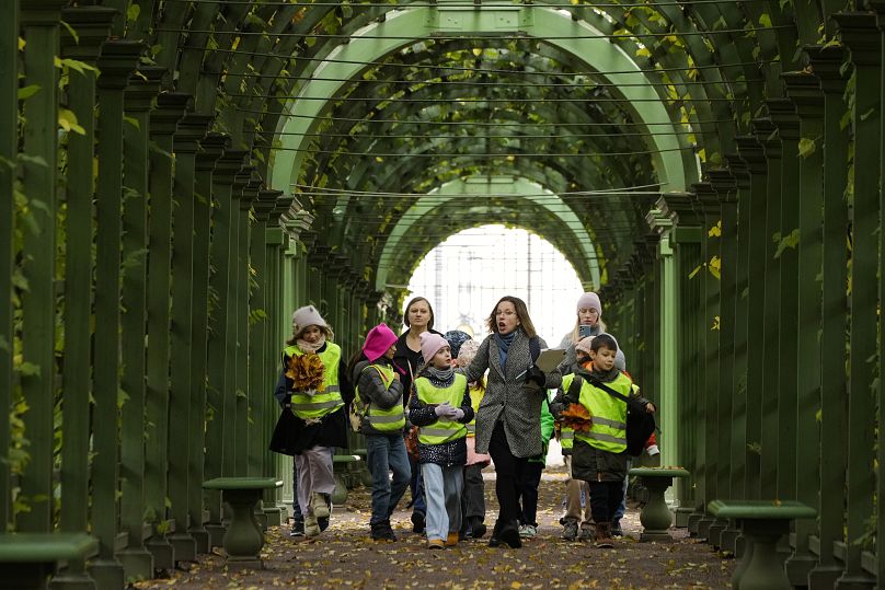 Des enfants marchent avec leur professeur dans le jardin d'été de Saint-Pétersbourg, le 16 octobre 2024