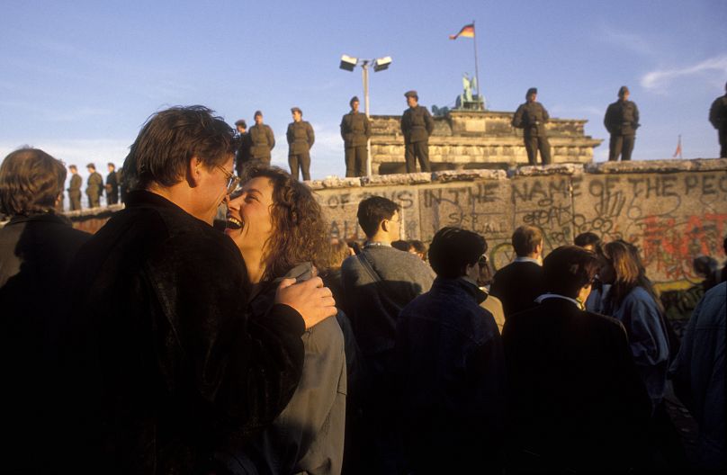 Un couple rient ensemble du côté ouest du mur de Berlin alors que les premières personnes commencent à traverser Berlin-Est en novembre 1989.