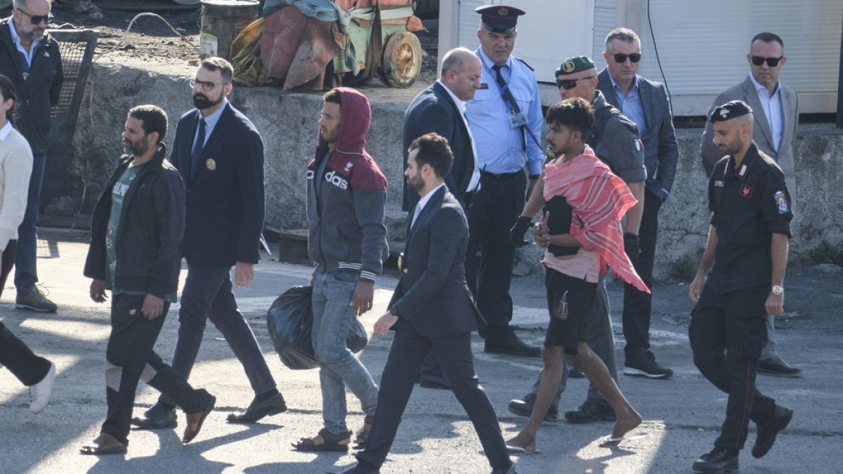 Migrant and security officials walk at the port of Shengjin, northwestern Albania. Wednesday, Oct. 16, 2024