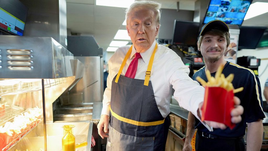 Donald Trump hands off an order of fries after working alongside an employee during a visit to McDonald