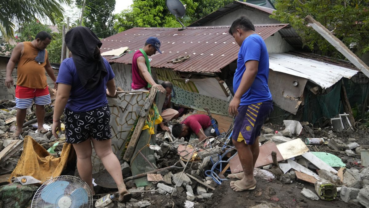 Residents try to recover personal belongings from their damaged home after a landslide triggered by Tropical Storm Trami recenprovince, Philippines on Saturday, Oct. 26, 2024.