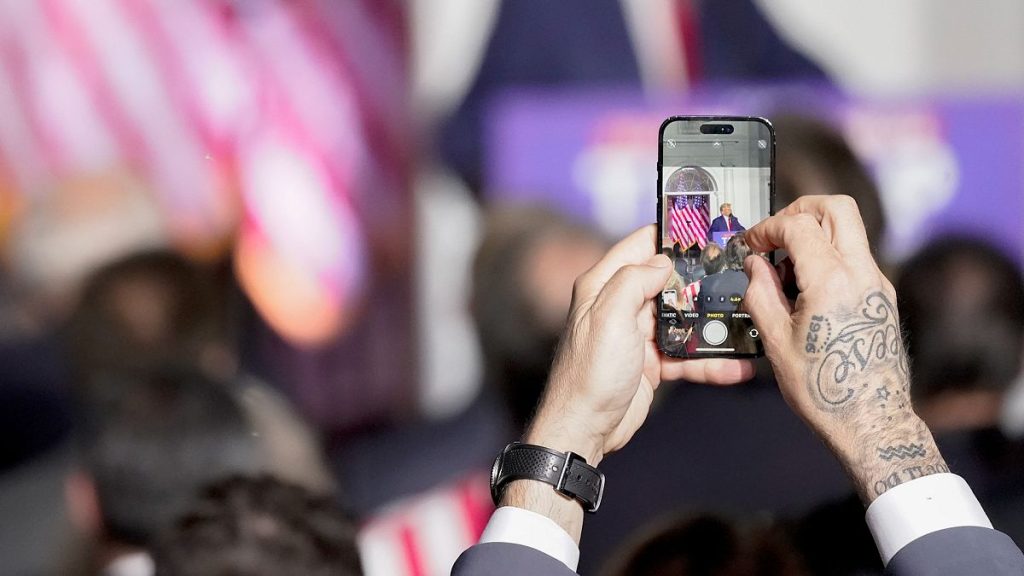 A supporter of former President Donald Trump takes a photo as Trump speaks at Trump National Golf Club Bedminster, 13 June 2023