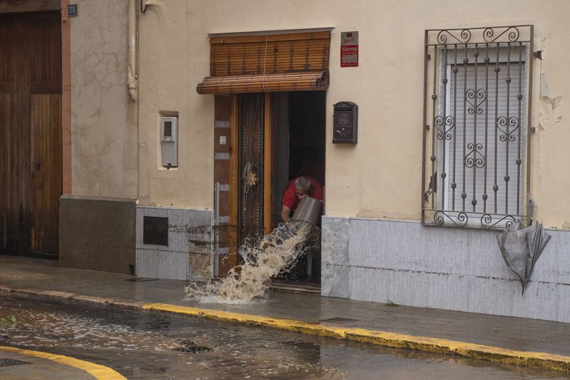 Un homme jette de l'eau hors de sa maison après les inondations à Valence, en Espagne