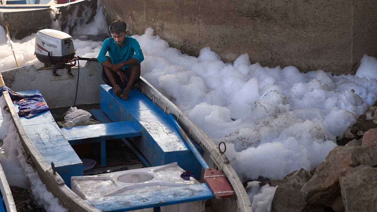 A worker for the Delhi Jal or water board sits in his boat in the river Yamuna filled with toxic foams in New Delhi, India, Tuesday, Oct. 29, 2024.