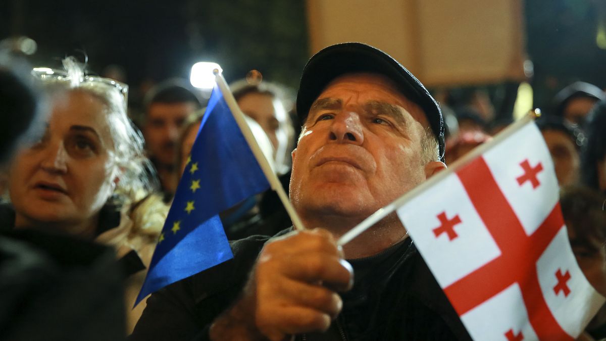 A demonstrator holds an EU and a Georgian national flags attending an opposition protest against the results of the parliamentary election in Tbilisi, Georgia, Oct.28,2024