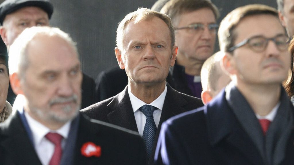 Donald Tusk (centre) stands behind Antoni Macierewicz (left) at a memorial