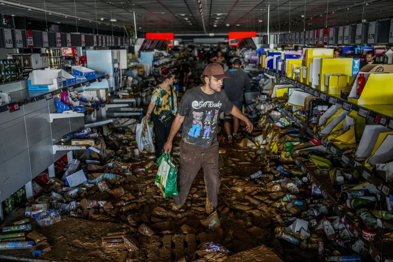 Des gens récupèrent des marchandises dans un supermarché touché par les inondations à Valence, en Espagne.