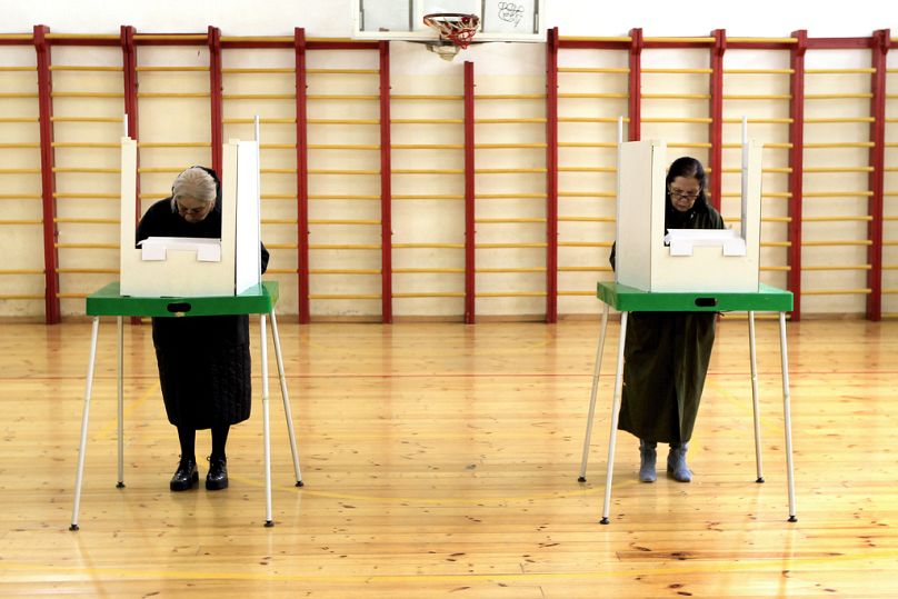 Des femmes remplissent leurs bulletins de vote dans un bureau de vote lors des élections législatives à Tbilissi, le 26 octobre 2024