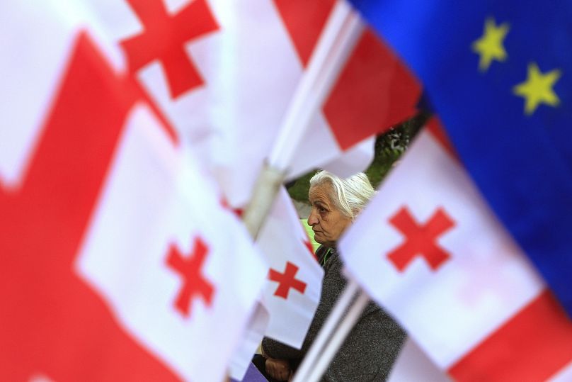 Une femme se tient parmi les drapeaux géorgiens lors d'une manifestation de l'opposition contre les résultats des élections législatives à Tbilissi, le 28 octobre 2024.