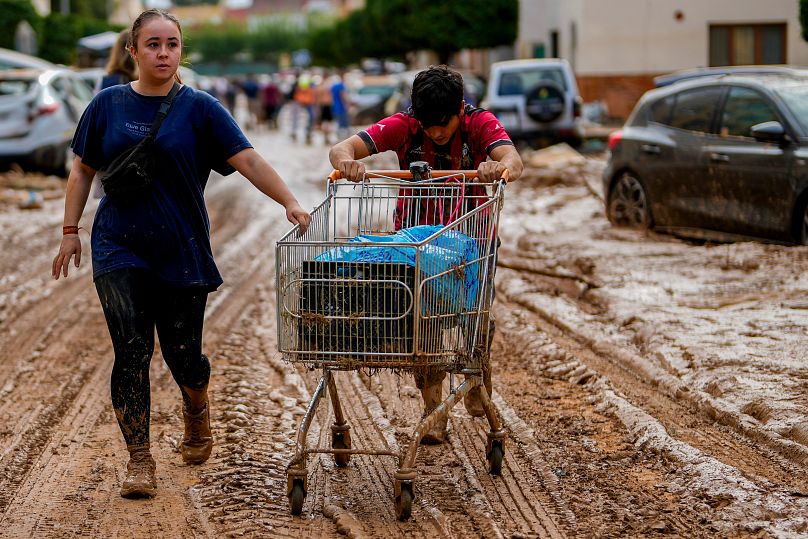 Deux personnes poussent un chariot chargé d'affaires à Valence, en Espagne, le jeudi 31 octobre 2024. 