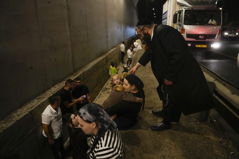 Des gens se cachent au bord d'une route alors qu'une sirène retentit pour avertir de l'arrivée de missiles tirés depuis l'Iran sur une autoroute à Shoresh, entre Jérusalem et Tel Aviv en Israël. 