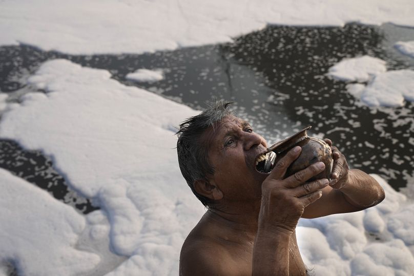 Jasraj, 70 ans, boit de l'eau de la rivière Yamuna remplie de mousse toxique à New Delhi, en Inde, le mardi 29 octobre 2024.