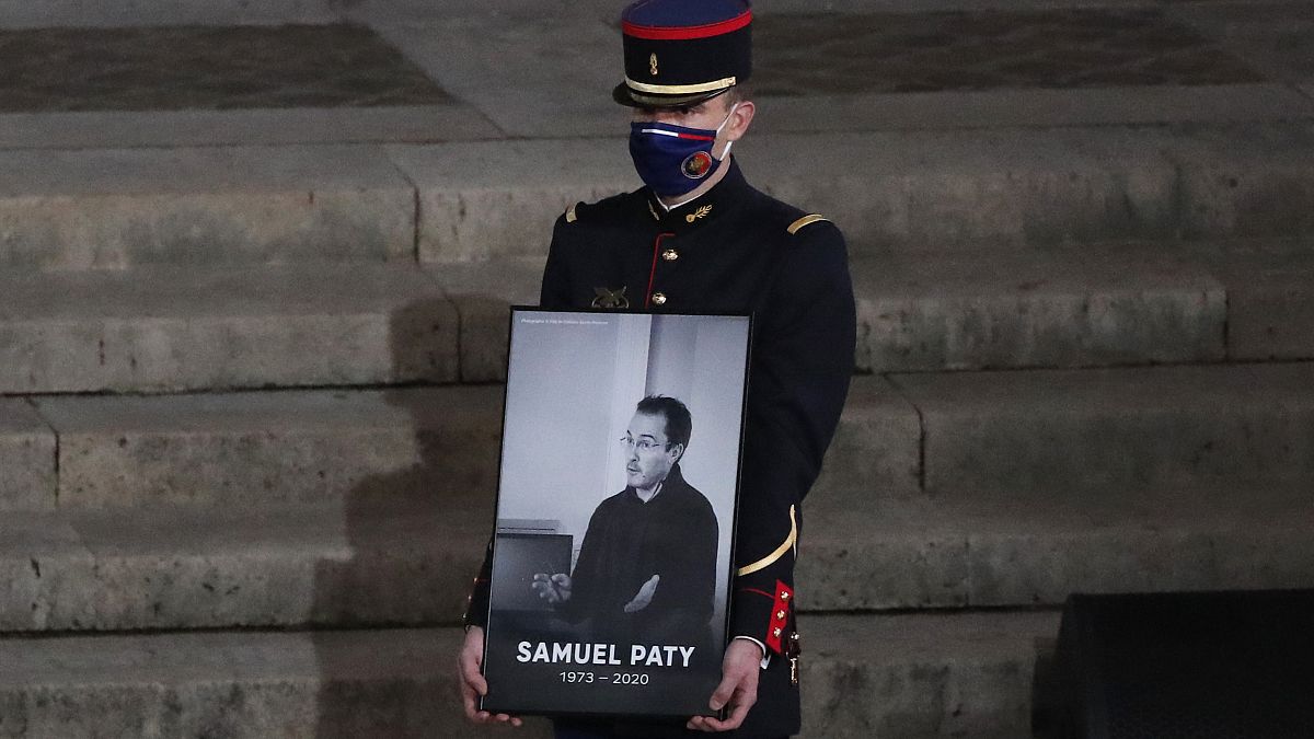 Republican Guard holding a portrait of Samuel Paty