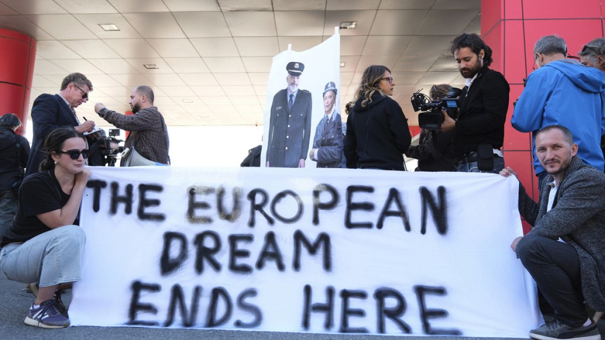 Activists, holding pictures of the Italian and Albanian premiers dressed as police officers, protest at the entrance of the port of Shengjin, northwestern Albania, Wednesday,