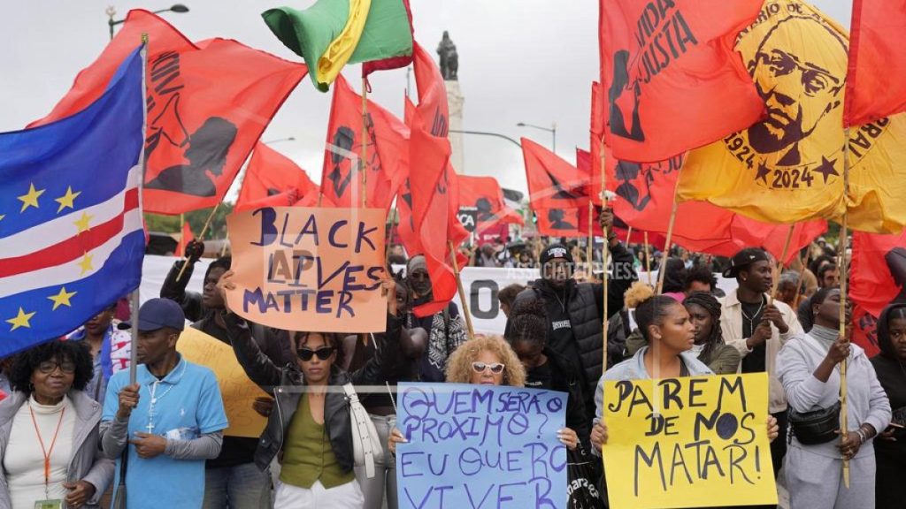 People carry signs and flags during a protest against racism and police violence after Odair Moniz, a Black man of Cape Verdean origin, was shot dead by police last Monday, in