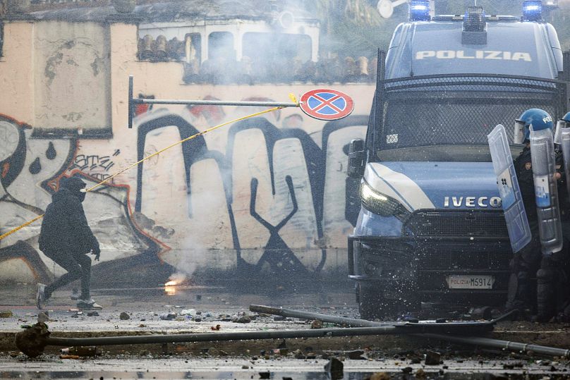 Une personne lance un panneau de signalisation en direction de la police anti-émeute alors que des manifestants affrontent la police lors d'une manifestation de soutien aux Palestiniens à Rome, le 5 octobre 2024.