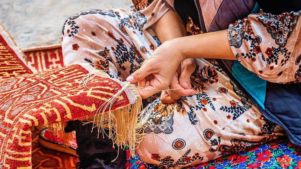 Detail of a female uzbek carpet weaver weaving a typical oriental uzbek silk carpet in Itchan Kala Old Town, Xiva - Khiva - Chiva, Xorazm Region, Uzbekistan, Central Asia