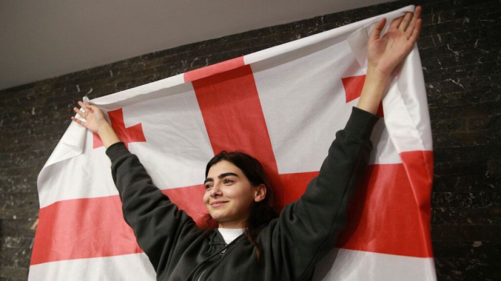 A supporter of the Coalition for Change holds a Georgian flag at coalition