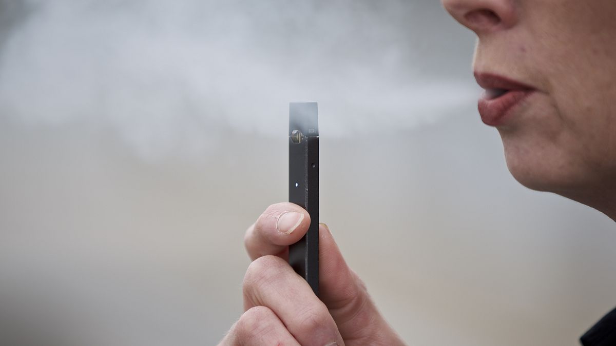 A woman exhales a puff of vapor from an e-cigarette in 2019.