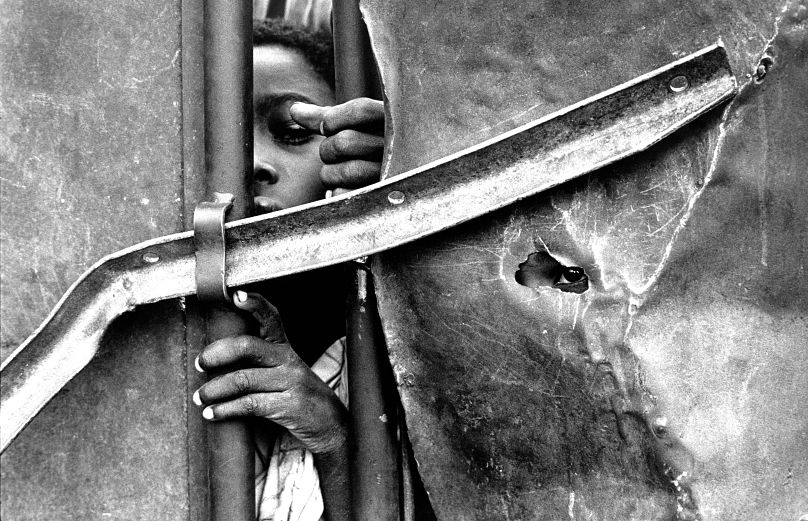 Des enfants regardent à travers les portes d’un centre de nutrition pendant une famine