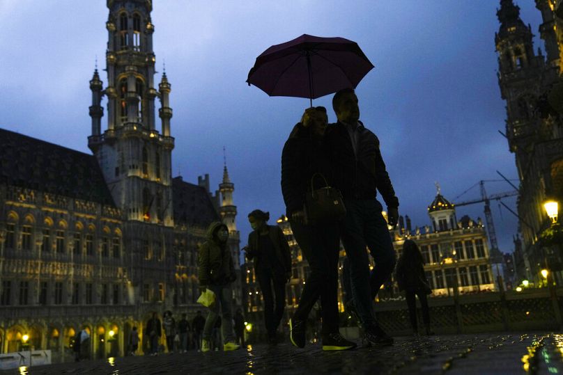 Les piétons s'abritent avec un parapluie contre la pluie sur la Grand Place ou la Grand Place du centre-ville de Bruxelles, juin 2021