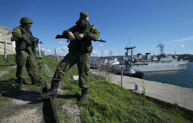 Des soldats russes gardent une jetée où sont amarrés deux navires de la marine ukrainienne, à Sébastopol, en mars 2014.