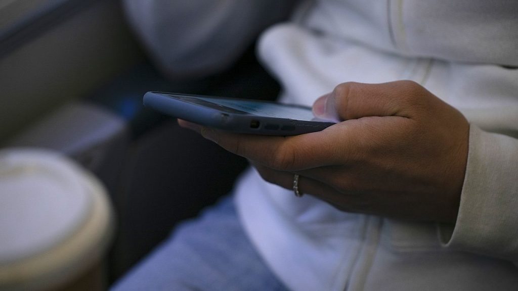 FILE - A woman looks at a hand held device on a train in New Jersey on May 18, 2021.