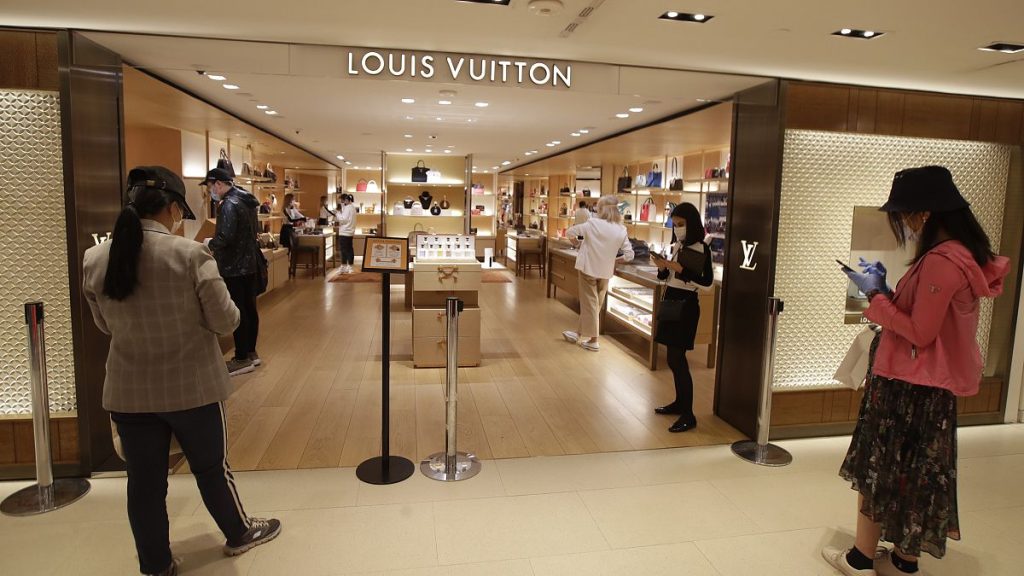 Customers wait in front of a luxury shop in Milan, Italy, Monday, May 18, 2020. Italy is slowly lifting sanitary restrictions after a two-month coronavirus lockdown.