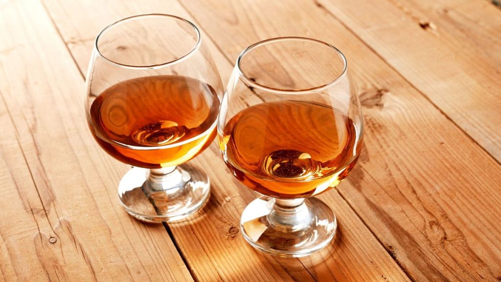 Two glasses of brandy on a wooden table