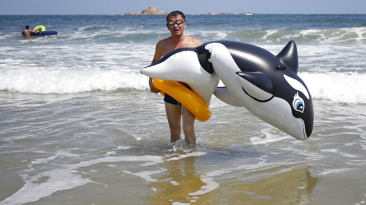 A man walks with an inflatable orca at Sijung Ho beach in North Korea before the pandemic - and borders closed