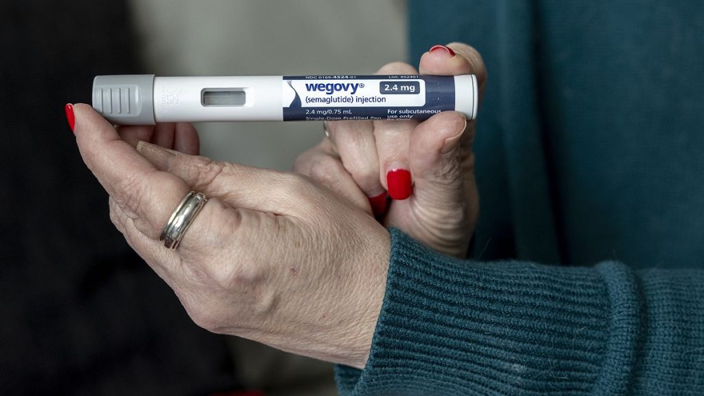 A woman holds up a dosage of Wegovy, a drug used for weight loss.