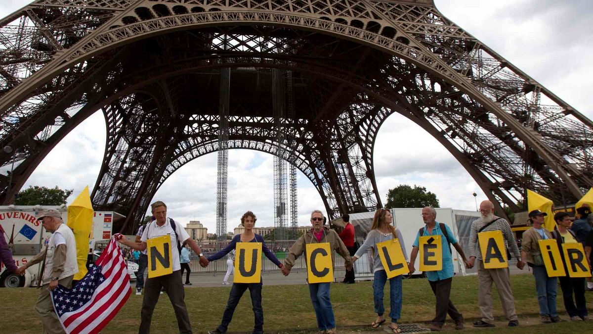 Anti nuclear activists form a human chain as they walk next to the Eiffel Tower, to mark 67th anniversary of the world