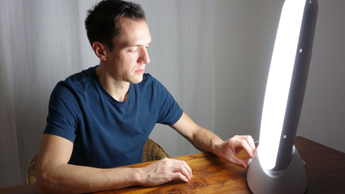 A man adjusts his light therapy box.