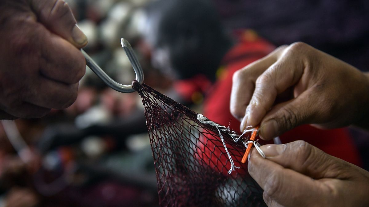 A Spanish fisherman mends a net.