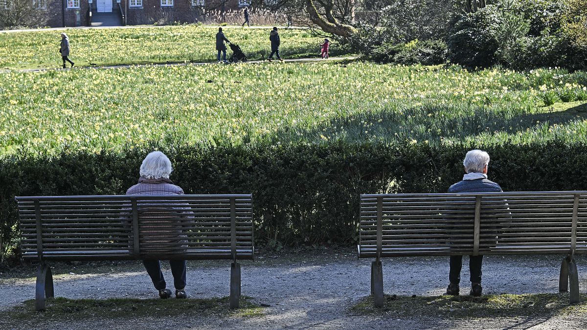 Two elderly women sit on park benches in Germany in 2020.