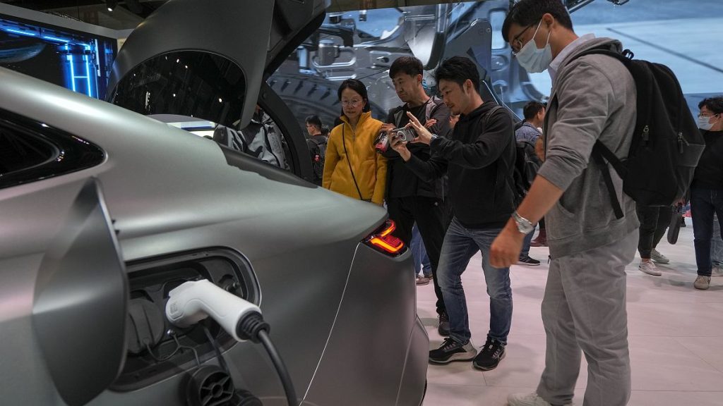 Visitors look at a Geely Galaxy E8 EV car model during the Auto China 2024 in Beijing. 28 April 2024.