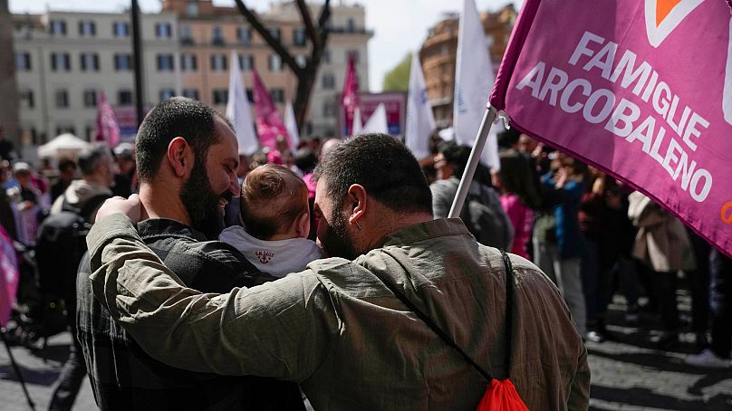 Stefano, à gauche, et Alessandro posent pour une photo avec leur fille lors d'un flash-mob pro-GPA à Rome, le vendredi 5 avril 2024