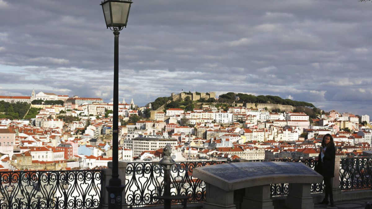 A woman stands at a viewpoint overlooking Lisbon