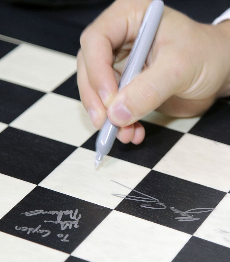 Le grand maître Magnus Carlsen signe un échiquier au Chess Club et au Centre scolaire de Saint-Louis, le mardi 26 août 2014 à Saint-Louis.