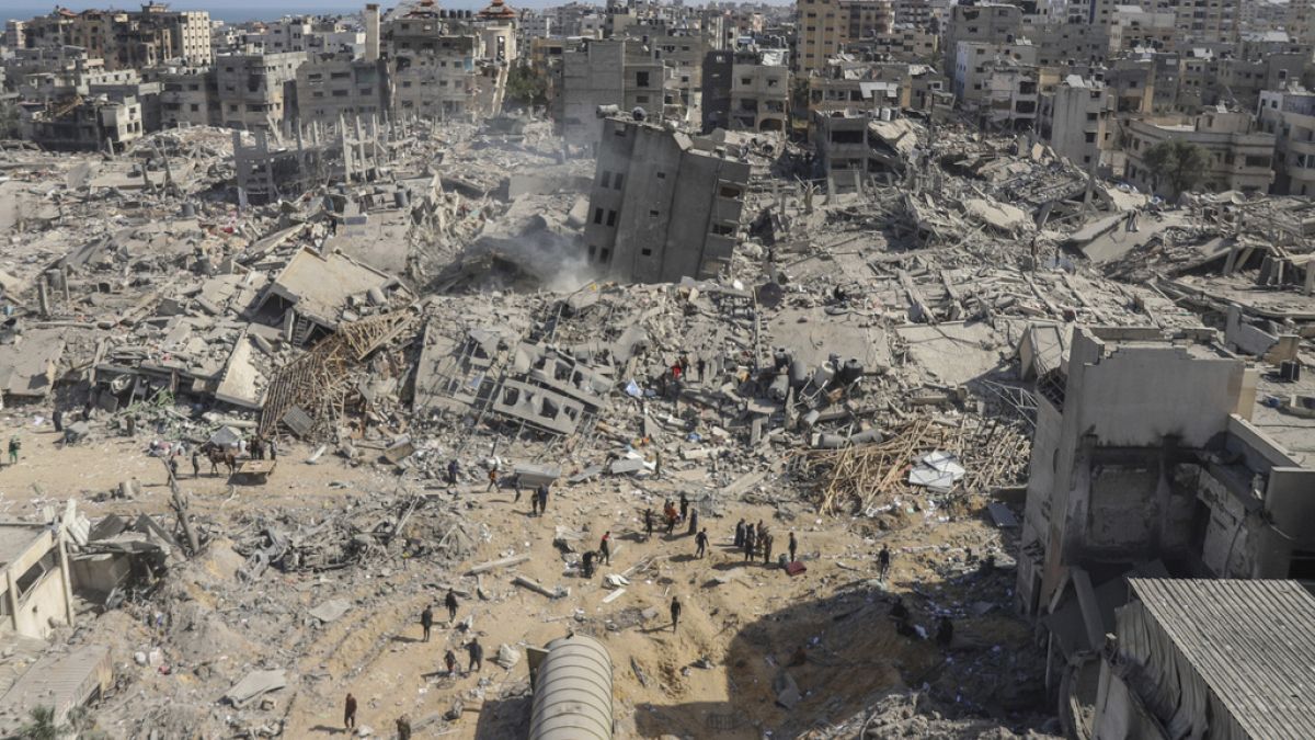 FILE - Palestinians walk through the destruction left by the Israeli air and ground offensive on the Gaza Strip near Shifa Hospital in Gaza City, Monday, April 1, 2024.