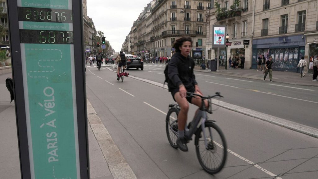 A man rides past a bicycle counter in Paris, Wednesday, Sept. 13, 2023.