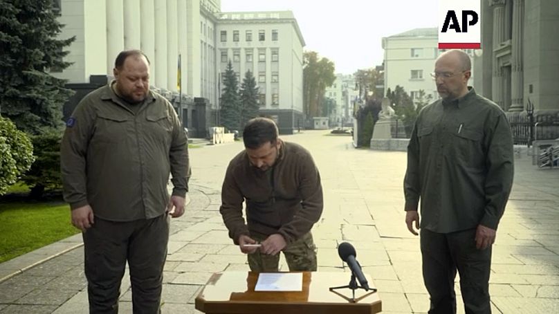 Dans cette image tirée d'une vidéo, Volodymyr Zelenskyy, avec le Premier ministre ukrainien et le chef de la Verkhovna Rada, signent une demande d'adhésion ''accélérée à l'OTAN''. 