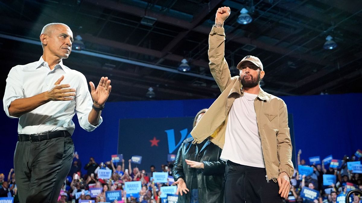 Rapper Eminem greets the crowd on stage with former President Barack Obama on Tuesday, 22 October at a campaign rally in Detroit.