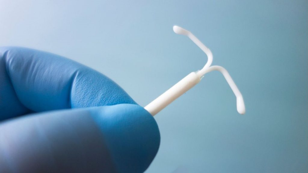 A medical worker holds an IUD.