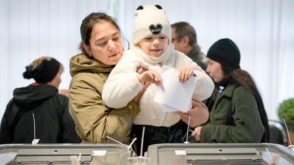 A woman holds a child as she casts her vote in Chisinau during a presidential election and a referendum on Moldova