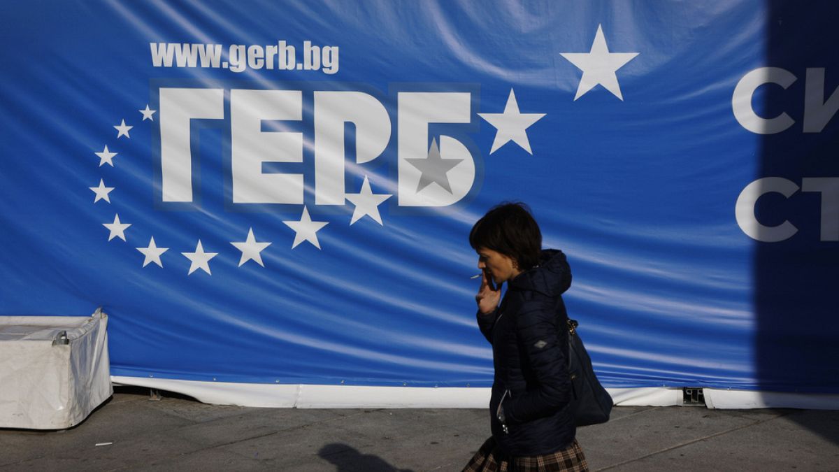 A woman walks in front of a GERB party poster Thursday, Oct. 24, 2024, in Sofia, as Bulgarians are called to cast ballots on Sunday