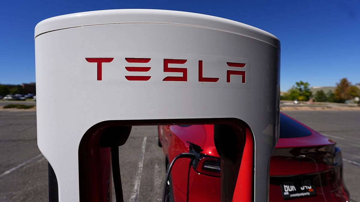 A Tesla Model 3 charges at a Tesla supercharging station in the parking lot in Lakewood, Colorado